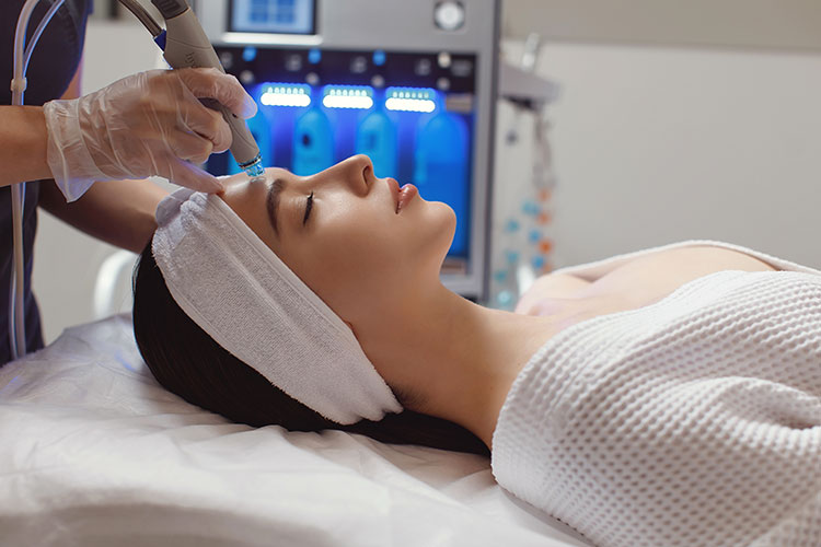 Woman lying down at spa getting a facial Deluxe Hydrafacial by Skinworks Wellness