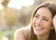 Beautiful brunnete woman lying in a field on a sunny day, smiling. What is vaginal rejuvenation.