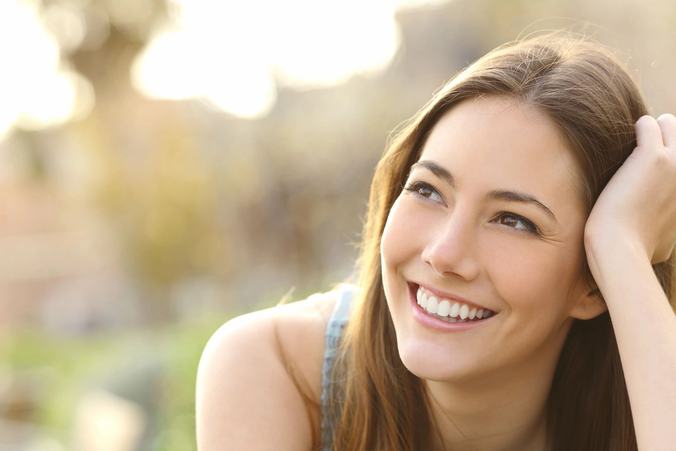 Beautiful brunnete woman lying in a field on a sunny day, smiling. What is vaginal rejuvenation.