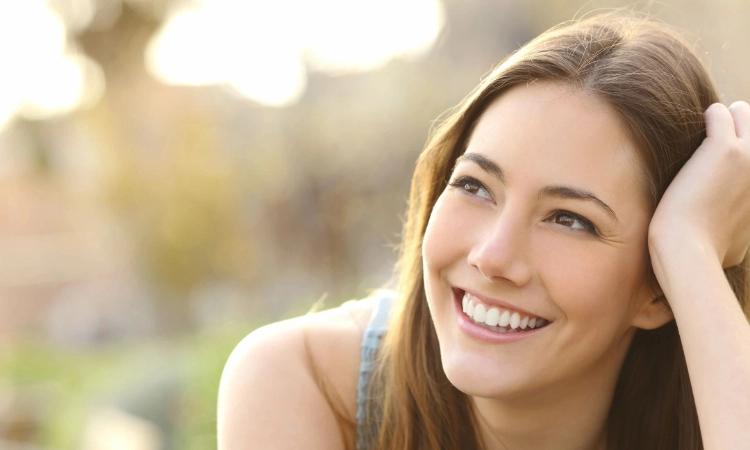 Beautiful brunnete woman lying in a field on a sunny day, smiling. What is vaginal rejuvenation.